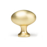 De Agero Gold Knop Deluxe van yessential.nl is een ovaalvormige meubelknop met een gladde, geborstelde gouden afwerking en een korte ronde voet, afgebeeld tegen een witte achtergrond.