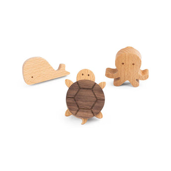 De Bambino Turtle van yessential.nl is klein houten speelgoed met eenvoudige uitgesneden details, afgebeeld met een walvis en octopus op een witte achtergrond. Ideaal als charmante houten meubelknop accessoires voor de kinderkamer.