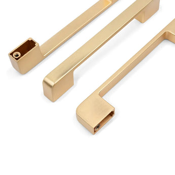 Drie Ramiro Gold Deluxe handgrepen van yessential.nl liggen op een witte achtergrond, twee plat en één schuin om het montagegat te tonen.