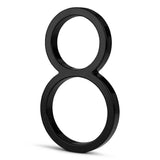 Een glanzend zwarte Amato Black 15cm van yessential.nl staat rechtop op een witte achtergrond en werpt een vage schaduw naar links - een strak voorbeeld van modern huisnummer design.