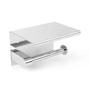 De Tazio Chrome toiletrolhouder van yessential.nl heeft een strak, modern design van chroom en een plat planchet voor kleine items, en is hier gemonteerd op een witte muur.