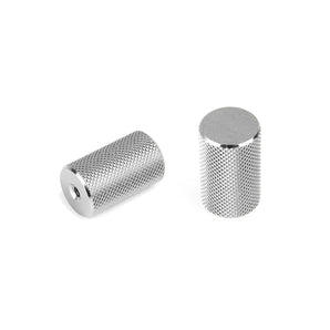 Twee cilindervormige, zilverkleurige Remo RVS Deluxe knoppen van yessential.nl met gekartelde oppervlakken - de ene horizontaal met het eindgat, de andere rechtop - vormen een stijlvol accent voor deuren of meubels op een effen witte achtergrond.