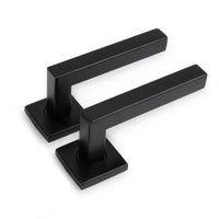 Twee Domaso Black deurklinken van yessential.nl, met vierkante voet en rechte horizontale hendels, worden getoond op een witte achtergrond.