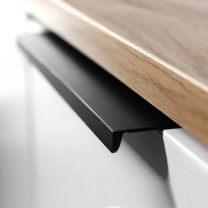 Een close-up van de Enzo Black ladegreep van yessential.nl, een moderne zwart metalen hoekgreep zwart, gemonteerd op een witte kast met een licht houten aanrecht erboven.