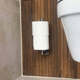 De Cosimo RVS WC Set van yessential.nl toont twee rollen toiletpapier verticaal gestapeld op een wandhouder, tegen een houten paneelwand in de badkamer.