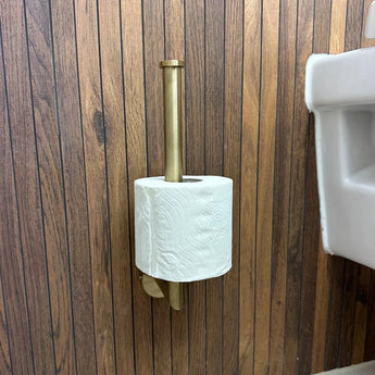 De Romano Gold WC set van yessential.nl heeft een enkele rol toiletpapier op een verticale gouden houder, gemonteerd op bruin houten lambrisering in de buurt van een witte wastafel.