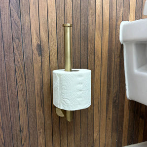 De Roberto Gold toiletrolhouder van yessential.nl, verticaal gemonteerd op een houten wand naast een witte wastafel, voegt een stijlvolle en elegante touch toe aan je badkameraccessoires.