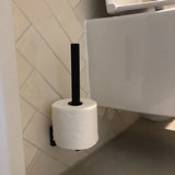 Een rol toiletpapier hangt verticaal aan de Bellino Black reserverolhouder van yessential.nl, bevestigd aan een betegelde badkamermuur naast een wit toilet.