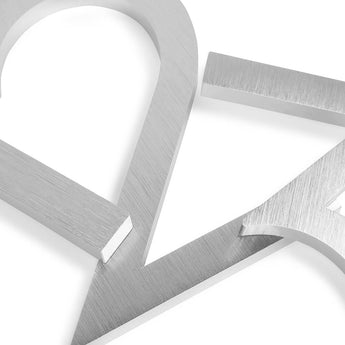 Close-up van kruisende Milano RVS 15cm huisnummers van yessential.nl, met geborstelde afwerking, strakke randen en een moderne geometrische look op een witte achtergrond.