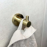 De Justo Gold Hook van yessential.nl houdt een lichtgrijze, getextureerde handdoek tegen een gladde, lichte muur.