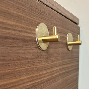 Close-up van twee gouden 4x Rudro Hooks 3M van yessential.nl horizontaal gemonteerd op lichtbruin hout met een zichtbaar nerfpatroon.