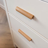 Close-up van eikenhouten handgrepen in een moderne minimalistische stijl. De lades maken deel uit van een kast op een lichthouten vloer.