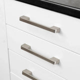 Close-up van drie witte keukenladen met moderne, rechthoekige Ramiro Chrome Deluxe handgrepen van yessential.nl in chroom, onder een strak zwart aanrechtblad.