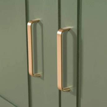 Close-up van yessential.nl's Leonardo Gold Deluxe handgrepen op groene kastdeuren met een verticaal groefontwerp, wat een luxe keukenstijl toevoegt.