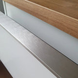 Close-up van een yessential.nl Enzo RVS keukenkast, met een RVS kleur profielhandgreep, wit front en houten aanrechtblad voor een strakke, minimalistische look.