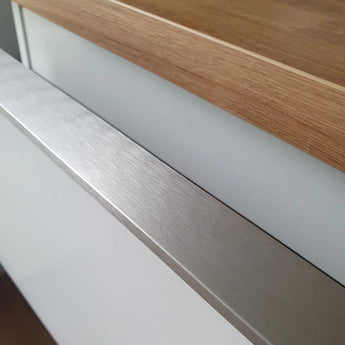 Close-up van een yessential.nl Enzo RVS keukenkast, met een RVS kleur profielhandgreep, wit front en houten aanrechtblad voor een strakke, minimalistische look.