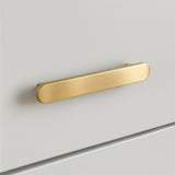 Een slanke Arriero Gold Deluxe ladegreep van yessential.nl is horizontaal gemonteerd op een gladde witte kast. Met afgeronde hoeken en een geborstelde gouden afwerking voegt het minimalistische ontwerp een vleugje luxe toe.