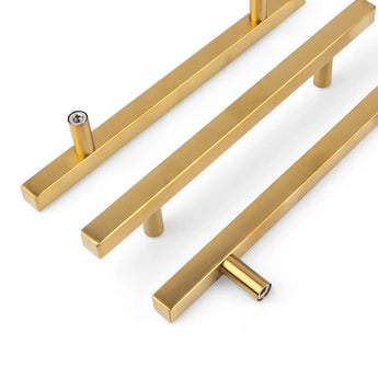 Drie Marano Gold handgrepen van yessential.nl, met een modern rechthoekig ontwerp met twee bevestigingspunten, zijn diagonaal geplaatst op een witte achtergrond - perfect als minimalistische accenten voor eigentijdse kasten of lades.