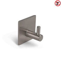 De Navarro Gunmetal van yessential.nl is een roestvrijstalen, zelfklevende haak met een vierkante basis en cilindervormige pin, weergegeven op wit. Een rood "niet boren" pictogram rechtsboven benadrukt de eenvoudige, boorvrije installatie.