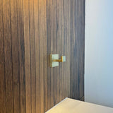 De Valo Gold Hook van yessential.nl is gemonteerd op een verticale houten paneelwand naast een wit vlak, met rechts een deel van een effen witte muur zichtbaar.