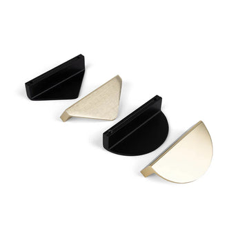 Vier yessential.nl Torno Black halve maan handgrepen worden getoond in zwart, geborsteld messing, mat zwart en gepolijst messing op een witte achtergrond, waarbij de elegante zwarte en metallic afwerkingen van de collectie worden benadrukt.