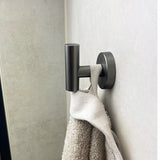 De Fabiano Gunmetal WC set van yessential.nl houdt een witte en beige handdoek op een lichte muur - een ideale, moderne touch voor je badkamer.