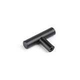 De Remo Black Knob van yessential.nl is een T-vormige zwarte metalen handgreep met een zeshoekig schroefgat, afgebeeld op een witte achtergrond. Ideaal als matzwart accent voor moderne kasten of lades.