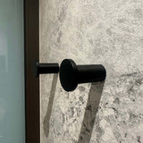Vier zwarte cilindrische Carreno handdoekhaakjes van yessential.nl, gemaakt van roestvrij staal, zijn gemonteerd op een gestructureerde wand van grijze steen - een elegante en moderne badkameraccessoire.