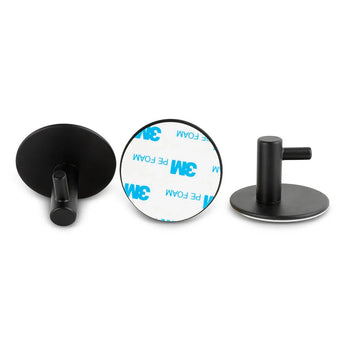 Er worden drie Rudro Black wandhaken van yessential.nl getoond: één met het gezicht naar voren, één met de ronde 3M-kleeflaag en één op zijn kant. Deze hoogwaardige haken geven een moderne, minimalistische touch aan elke witte achtergrond.