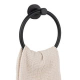 Een handdoek met beige structuur hangt aan de Elarbo Black handdoekring van yessential.nl, bevestigd aan een witte muur-een stijlvolle en ruimtebesparende oplossing voor elke badkamer.
