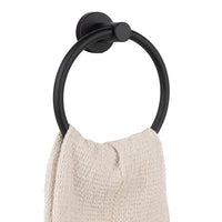 Een handdoek met beige structuur hangt aan de Elarbo Black handdoekring van yessential.nl, bevestigd aan een witte muur-een stijlvolle en ruimtebesparende oplossing voor elke badkamer.