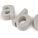 Twee 3D betonnen kleine letters "a" en "b" (Enrico beton 30cm by yessential.nl) staan op een witte achtergrond, waarbij de "b" opzij ligt en gedeeltelijk uit het beeld is geknipt.