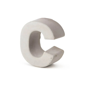 De Enrico beton 20cm van yessential.nl is een driedimensionale, lichtgrijze betonnen letter C die rechtop staat tegen een effen witte achtergrond, en benadrukt de look van een stijlvol huisnummer gemaakt van duurzaam beton.