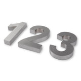 Drie Angelo RVS 20cm huisnummers (1, 2 en 3) van yessential.nl worden weergegeven op een wit oppervlak. Elk modern huisnummer heeft een geborstelde zilveren afwerking en een opvallend 3D-ontwerp dat subtiele schaduwen werpt aan de onderkant.