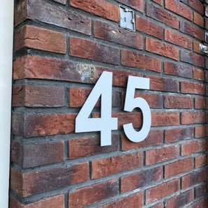 Het Adamo White 15cm huisnummer van yessential.nl valt op bij bakstenen muren en combineert een moderne stijl met een hoge zichtbaarheid voor een maximale impact.