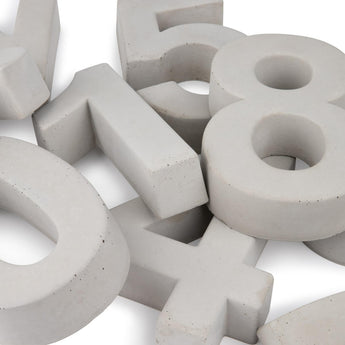 Een close-up van verschillende grote, lichtgrijze Enrico beton 20cm huisnummer figuren-0, 1, 5, 8, en 4-van yessential.nl verspreid op een witte achtergrond.