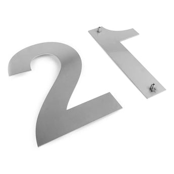 Twee grote metalen huisnummers, 2 en 1, uit de Adamo RVS 30cm lijn van yessential.nl, liggen plat op een wit oppervlak. Ze zijn gemaakt van geborsteld roestvrij staal en hebben stevige bevestigingspalen aan de achterkant.