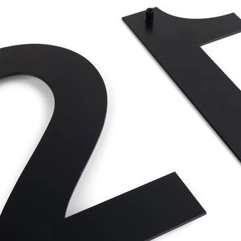 Twee Adamo Black 20cm huisnummers van yessential.nl, cijfers 2 en 1, liggen op een witte ondergrond. Het cijfer 1 heeft bovenaan een bevestigingspin-ideale moderne gevelnummers.