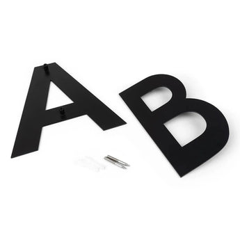 Twee zwarte Adamo Black 20cm letters A en B van yessential.nl, ideaal als moderne huisnummers, liggen op een wit oppervlak met meegeleverde bevestigingsmaterialen (schroeven en muurankers) ertussen.