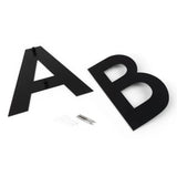 Twee grote, platte Adamo Black 15cm letters A en B van yessential.nl rusten op een wit oppervlak met muurbevestigingsschroeven en ankers-perfect als stijlvol rvs huisnummer zwart voor je huis.