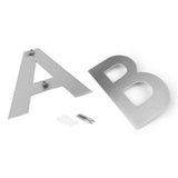 Twee metalen letters, A en B, zijn afgebeeld op een wit oppervlak. De A is voorzien van bevestigingsmateriaal, terwijl extra bevestigingsmateriaal en muurankers in de buurt de installatie eenvoudig maken - ideaal voor stijlvolle yessential.nl Adamo RVS 15cm huisnummers.