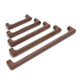 Vijf Salgado Walnut handgrepen van yessential.nl zijn diagonaal gerangschikt op grootte op een wit oppervlak. Ze hebben allemaal een eenvoudig, modern ontwerp met afgeronde hoeken, wat de minimalistische stijl van het merk benadrukt.