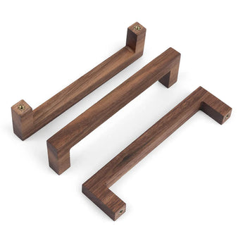 Drie Vasco Walnut handgrepen van yessential.nl met een minimalistisch, hoekig ontwerp worden weergegeven op een witte achtergrond. Elk rechthoekig stuk varieert in grootte en heeft zichtbare schroefgaten aan beide uiteinden voor eenvoudige bevestiging.