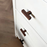 Close-up van de Vasco Walnut dressoir van yessential.nl, met witte lades met handgrepen van donker walnotenhout, getoond vanuit een schuin bovenaanzicht tegen een houten vloer.
