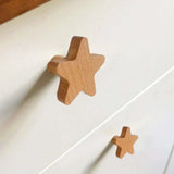 Twee Bambino Star houten knoppen van yessential.nl zijn bevestigd aan een witte commode, met één knop dichter bij de camera - een ideale manier om charme en stijl toe te voegen aan elke kinderkamer knopjes collectie.