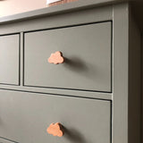 Een close-up van een saliegroen dressoir met Bambino Cloud houten meubelknop van yessential.nl in een speels wolkendessin. De gladde, matte afwerking en eenvoudige lijnen maken het perfect voor een minimalistische en vrolijke kinderkamer.