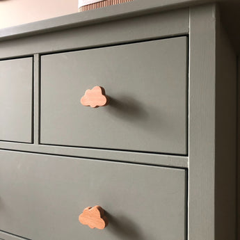 Een close-up van een saliegroen dressoir met Bambino Cloud houten meubelknop van yessential.nl in een speels wolkendessin. De gladde, matte afwerking en eenvoudige lijnen maken het perfect voor een minimalistische en vrolijke kinderkamer.