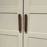 Een paar Arriero Walnut kastdeuren van yessential.nl heeft verticale houten handgrepen die dicht bij elkaar in het midden zijn geplaatst, waardoor een optische illusie ontstaat die doet denken aan een bruine hotdog.
