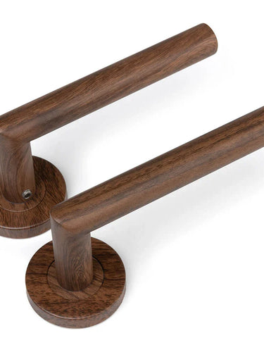 De Lucio Walnut Set van yessential.nl bestaat uit twee moderne cilindervormige houten deurklinken met ronde voet, parallel geplaatst op een witte achtergrond.