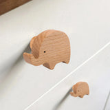 Twee lichte houten Bambino Olifantenknoppen van yessential.nl, een grote en een kleine, zijn bevestigd aan een witte lade. Hun speelse ontwerp voegt een minimalistisch tintje toe - perfect als accenten in de kinderkamer.